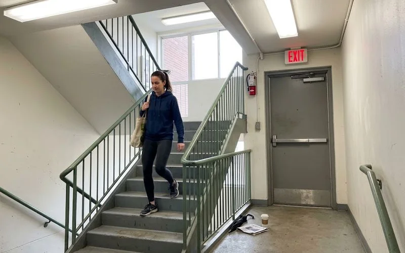 A stairwell exit sign in a high-rise apartment building hallway with emergency lighting visible